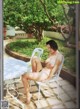 A naked woman sitting on a white chair in a garden.